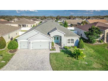 Beautiful one-story home featuring a well-manicured lawn, three-car garage, and a charming light-blue front door at 6148 Gracie Pl, Lakeland, FL 33812