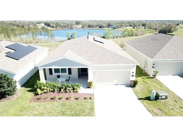 Inviting single-story home with solar panels, a two-car garage, and a cozy front porch, near a scenic lake at 954 Laurel View Way, Groveland, FL 34736