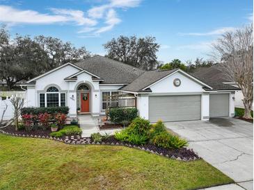 Charming single-story home with well-manicured landscaping, three car garage and a beautiful orange front door at 10987 Piping Rock Cir, Orlando, FL 32817