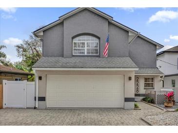 Charming two-story gray home features a wide two car garage with a paved driveway, and an American flag at 2228 Hoffner Ave, Belle Isle, FL 32809