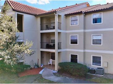 Three-story condo building featuring a spanish tile roof, beige exterior, and private balconies at 3016 Parkway Blvd # 110, Kissimmee, FL 34747