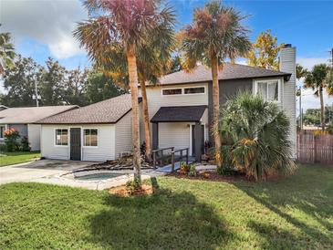 Charming two-story home with a well-manicured lawn and tropical landscaping with mature palm trees at 1040 Waverly Dr, Longwood, FL 32750