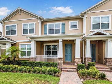 Charming two-story townhome showcasing a welcoming front porch, colorful door and well-maintained landscaping at 15574 Murcott Blossom Blvd, Winter Garden, FL 34787