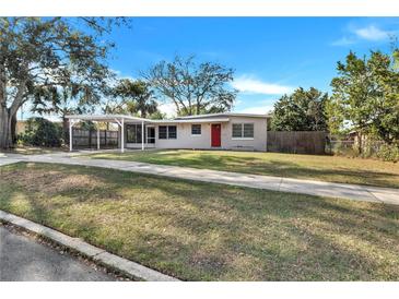Charming single story home with carport, red front door, and well-maintained lawn at 1202 Ferndell Rd, Orlando, FL 32808