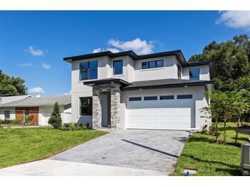 Contemporary two-story home featuring stone accents, a brick driveway, and a spacious two-car garage at 1807 Simonton Ave, Orlando, FL 32806