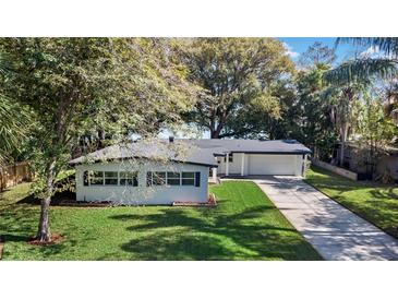 Charming single-story home with a well-manicured lawn, mature trees, and an attached two-car garage at 2913 Carmia Dr, Orlando, FL 32806