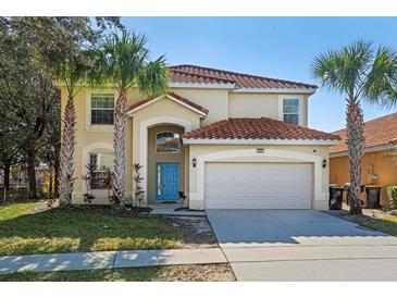 Two-story house featuring a terra cotta tile roof, a two-car garage, and a blue front door at 390 Miro Dr, Davenport, FL 33837