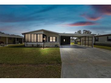 Dusk view of home with a screened-in porch and covered carport, set against a beautiful twilight sky at 721 Polo Park Blvd, Davenport, FL 33897