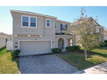 Two-story home featuring a neutral stucco finish, arched entryway, paver driveway, and attached two-car garage at 917 Carmillion Ct, Groveland, FL 34736