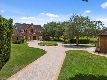 Expansive front yard featuring a circular driveway, lush landscaping, and a beautiful brick home at 9501 Tavistock Rd, Orlando, FL 32827