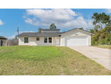 Charming single-story home with a well-manicured lawn, an attached two-car garage, and a welcoming front entrance at 1597 Lansfield Ave, Deltona, FL 32738