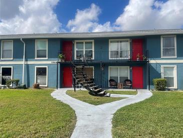 Two-story apartment building featuring vibrant red doors and balconies with seating areas, set against a blue facade at 1866 Caralee Blvd # 3, Orlando, FL 32822