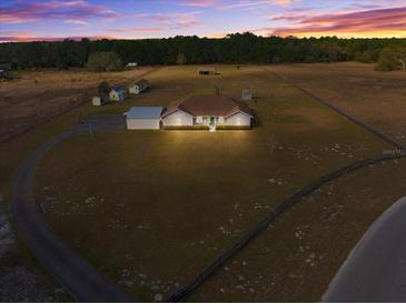 Areal view of charming home with brick accents, green front door, a large yard, and outbuildings at 36525 Reserve Dr, Eustis, FL 32736