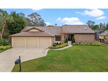 Charming one-story home with a three-car garage, lush landscaping, and a brick accent wall at 6766 Edgeworth Dr, Orlando, FL 32819
