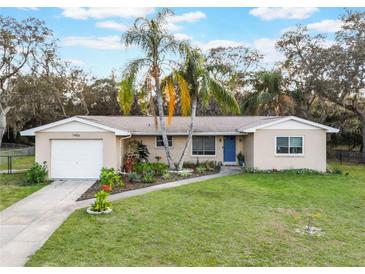 Charming single-story home featuring lush landscaping, a well-manicured lawn, and a welcoming blue front door at 1456 Helena Ct, Deltona, FL 32725