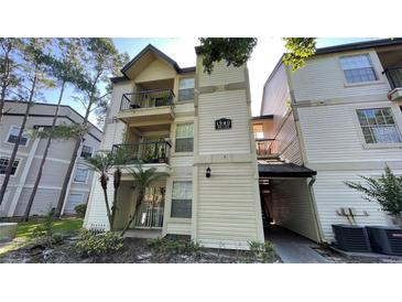 Multi-level condo with balconies, light siding, mature trees, and well-maintained landscaping at 1940 Lake Atriums Cir # 108, Orlando, FL 32839