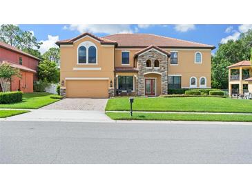 Two-story home with tile roof, manicured lawn, and brick driveway on a sunny day at 2926 Falconhill Dr, Apopka, FL 32712