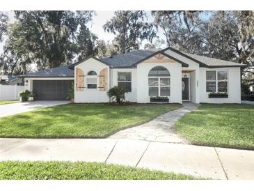 Charming single-story home with white brick, shutters, manicured lawn, and mature landscaping at 297 N Lake Jessup Ave, Oviedo, FL 32765