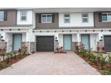 Townhome exterior with brick accents, a driveway, and a blue front door at 3031 Pilot House Pl, Oviedo, FL 32765