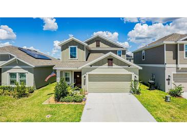 Charming two-story home features a two-car garage, green lawn, and well-maintained landscaping at 1043 John Jacob Rd, Davenport, FL 33837