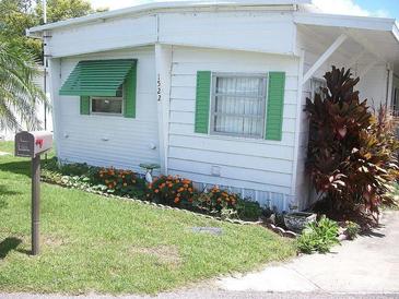 Charming home exterior featuring green shutters, tidy landscaping with orange flowers and a well-maintained lawn at 1522 S Shore Dr, Tavares, FL 32778