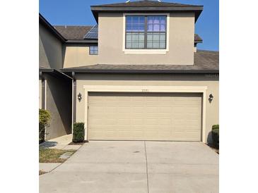 Beige two-car garage door on a tan two-story home with well-maintained front lawn at 2355 Seven Oaks Dr, St Cloud, FL 34772