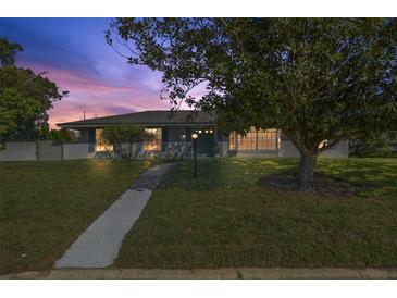 Charming home with a well-manicured lawn and mature tree casting shadows on the front yard at twilight at 2595 Sweetwater Trl, Maitland, FL 32751