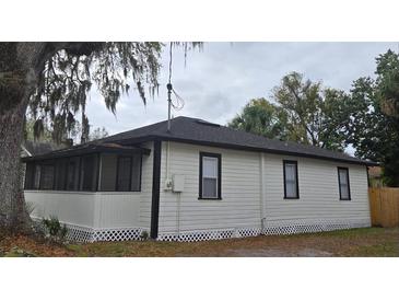 Charming home exterior featuring a screened porch, crisp white siding, and black trim under a cloudy sky at 812 S Locust Ave, Sanford, FL 32771