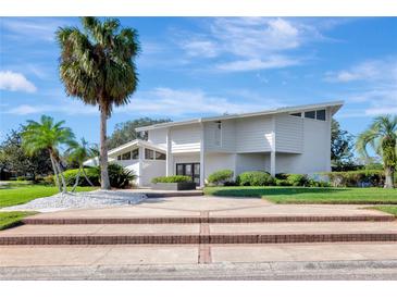 Stunning two-story white home featuring a lush landscaped yard and entryway with palm tree, offering great curb appeal at 8922 Bay Cove Ct, Orlando, FL 32819