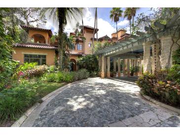 Spacious stone driveway leading to a home with a portico and lush landscaping at 9291 Point Cypress Dr, Orlando, FL 32836