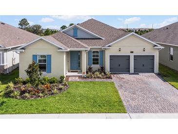 Charming single-story home with a well-manicured lawn, colorful landscaping, and a two-car garage at 18955 Rawson St, Orlando, FL 32827