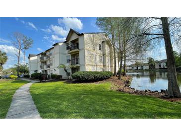 Inviting exterior view of the condo building with beautiful landscaping and a serene pond at 1948 Lake Atriums Cir # 113, Orlando, FL 32839