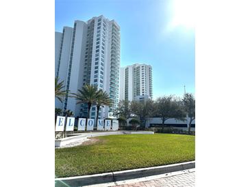 Exterior view of high-rise condos with 'Welcome' sign and landscaping on a sunny day at 231 Riverside Dr # 1510-1, Daytona Beach, FL 32117