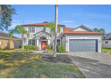 Charming two-story home with a red front door, a manicured lawn, and a two car garage at 248 Isle Of Sky Cir, Orlando, FL 32828