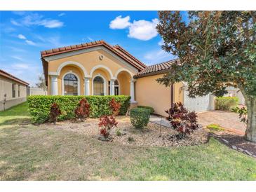 Charming home featuring manicured landscaping, a tile roof, and a quaint front yard with lush green foliage at 323 Villa Sorrento Cir, Haines City, FL 33844