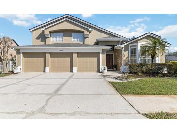 Two-story home with a tan exterior and a three-car garage with a well-maintained lawn and landscaping at 3262 Amaca Cir, Orlando, FL 32837