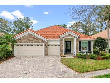 Charming single-story home featuring a red tile roof, stone accents, a three-car garage, and a welcoming front entrance at 448 Douglas Edward Dr, Ocoee, FL 34761