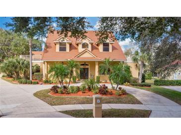 Charming two-story home with a tile roof, manicured landscaping, and a circular driveway at 7655 Debeaubien Dr, Orlando, FL 32835