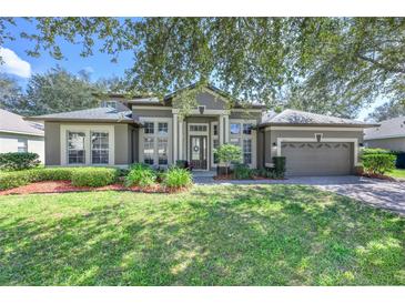 Charming single-story home with well-maintained lawn, mature landscaping, and a two-car garage at 814 Kazaros Cir, Ocoee, FL 34761