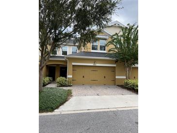 Two story tan home with a two car garage, brick paver driveway, and well maintained landscaping at 8237 Serenity Spring Dr # 2605, Windermere, FL 34786