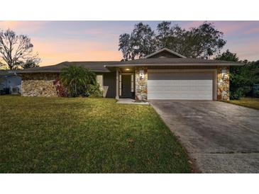 Charming single-story home featuring a stone facade and well-manicured lawn at 104 E Cottesmore Cir, Longwood, FL 32779