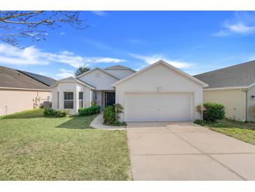 Charming single-story home with well-maintained landscaping and a two-car garage at 1047 Bluegrass Dr, Groveland, FL 34736