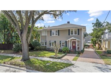 Charming two-story home featuring a well-manicured lawn, awnings, and a welcoming red front door at 1508 Delaney Ave, Orlando, FL 32806