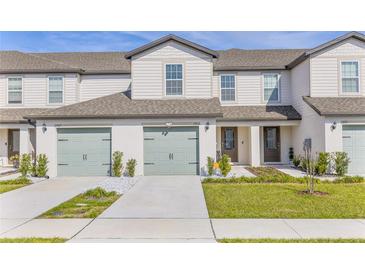 Charming townhome featuring a two-car garage, manicured lawn, and a welcoming front entrance at 1703 Wynford Cir, Tavares, FL 32778