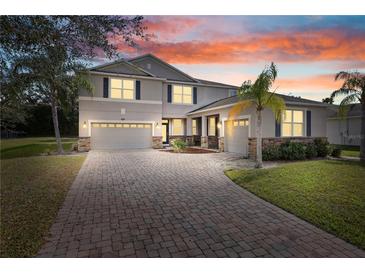 Charming home with a two-car garage, brick-paved driveway and lush landscaping at dusk at 3819 Breckinridge Ln, Clermont, FL 34711