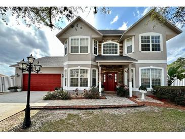 Beautiful two-story home featuring a red front door with brick accents and a red two-car garage door at 546 Nogales Ct, Kissimmee, FL 34758