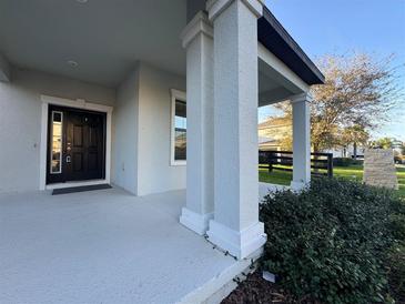 Inviting front porch features stately columns and a stylish front door with sidelights at 7606 Loon Ave, Winter Garden, FL 34787