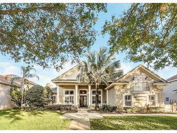 Elegant home with mature landscaping, a palm tree, and a stately columned entrance at 10742 Boca Pointe Dr, Orlando, FL 32836