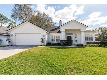 Charming single-story home with a well-manicured lawn, attached garage, and white stucco exterior at 1165 Cardinal Creek Pl, Oviedo, FL 32765