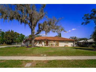 Charming single-story home featuring a red tile roof and lush front yard at 14 E Cypress St, Davenport, FL 33837